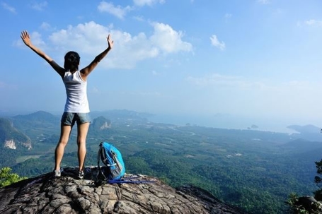 woman climbing to top of mountain