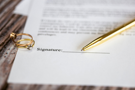 wedding rings, a pen, and a document to be signed