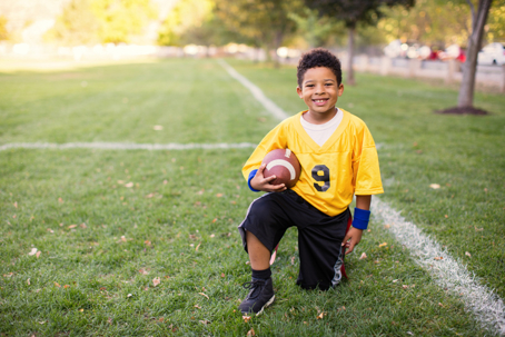 happy child in uniform holding football